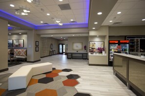 A hotel lobby with a reception desk, seating area, and a counter with a menu. - Hampton Inn Blue Ash/Cincinnati (Cincinnati)