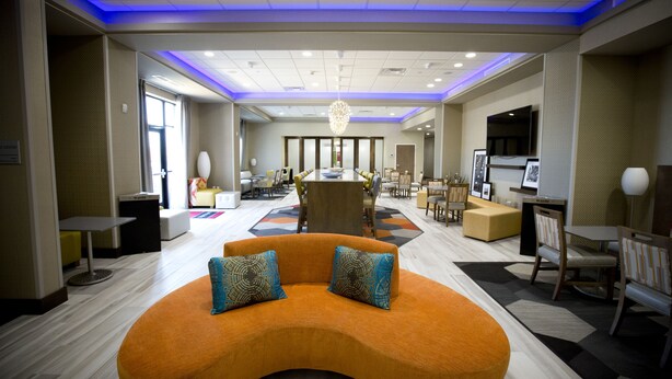 A hotel lobby with a central seating area, a dining area, and a TV mounted on the wall. - Hampton Inn Blue Ash/Cincinnati (Cincinnati)