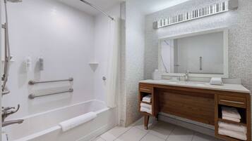 A modern bathroom with a bathtub, a vanity with a mirror, and a shower area.