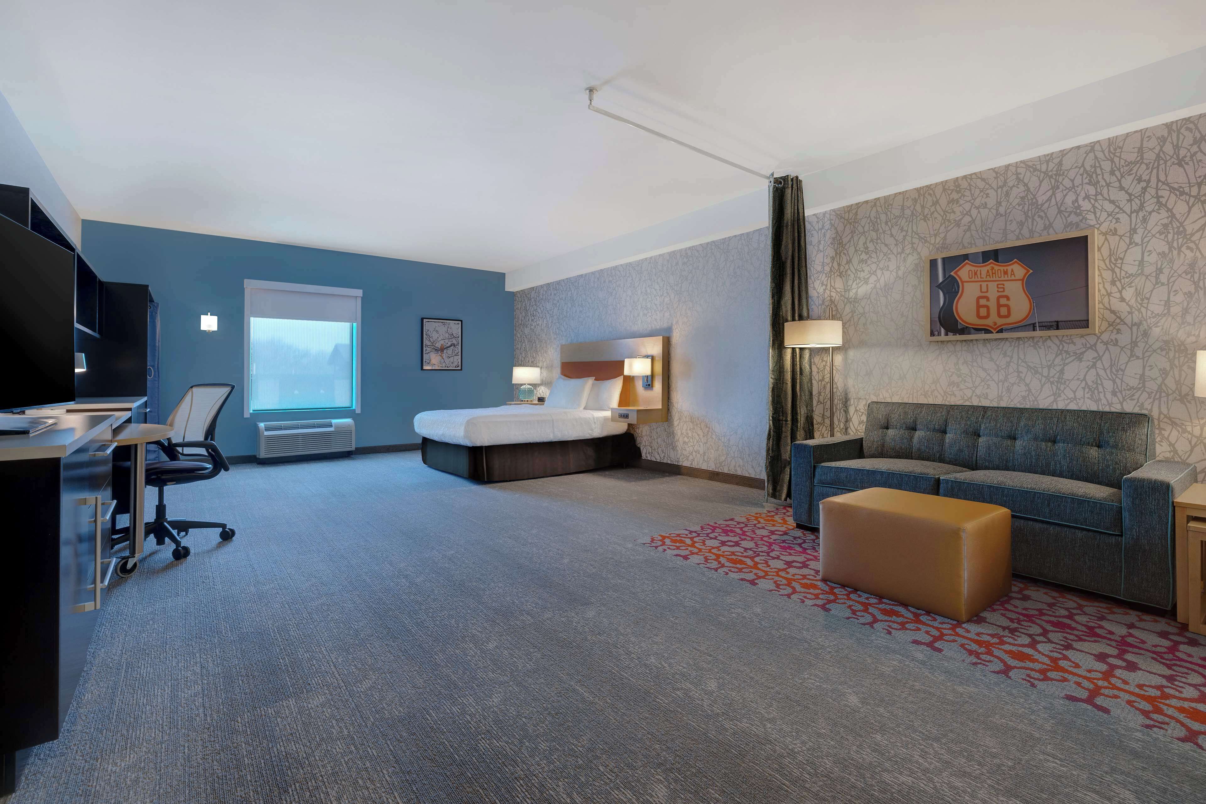 Una habitación de hotel con cama, sofá, escritorio y televisor.
