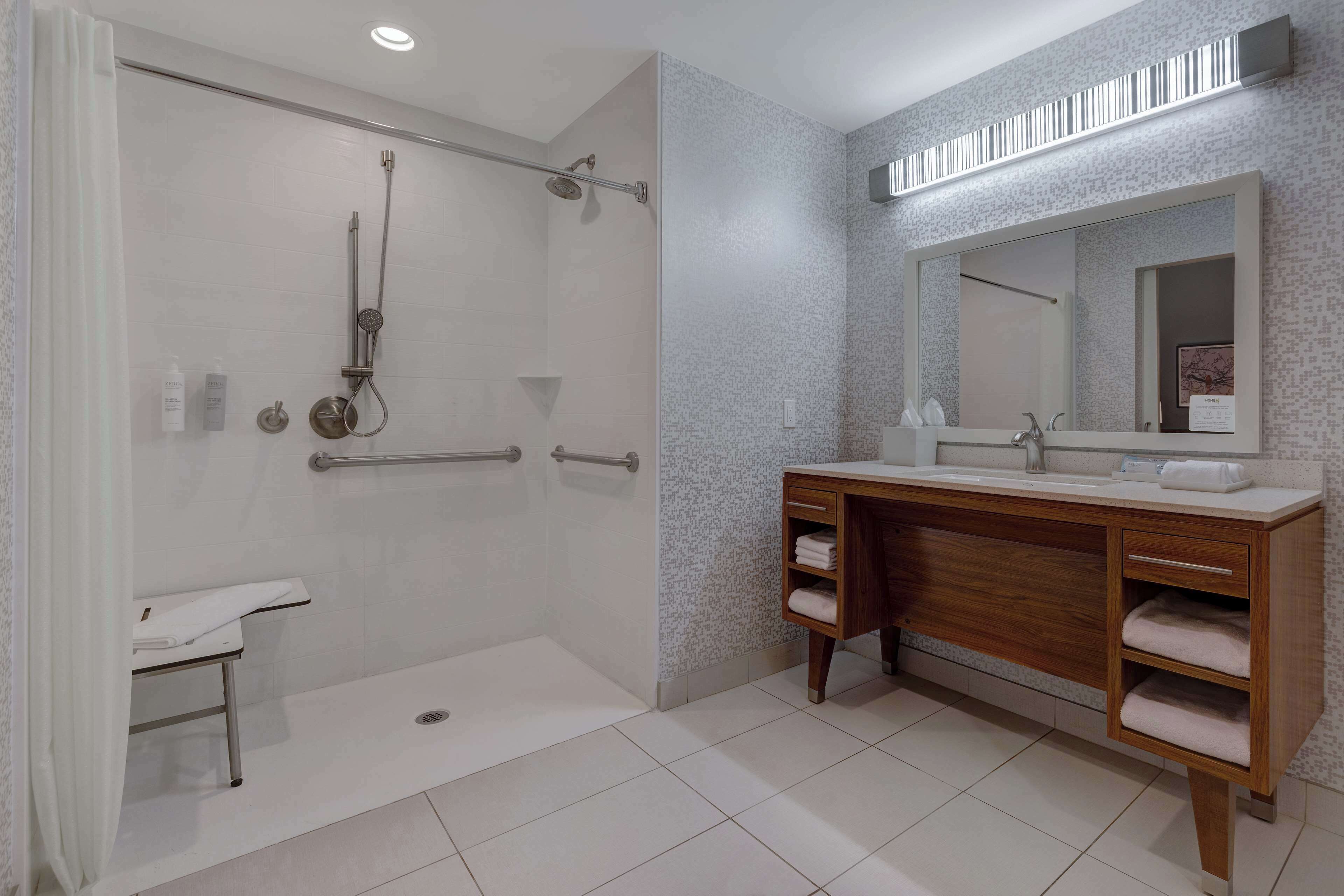 A modern bathroom with a walk-in shower, a vanity with a large mirror, and a towel rack.