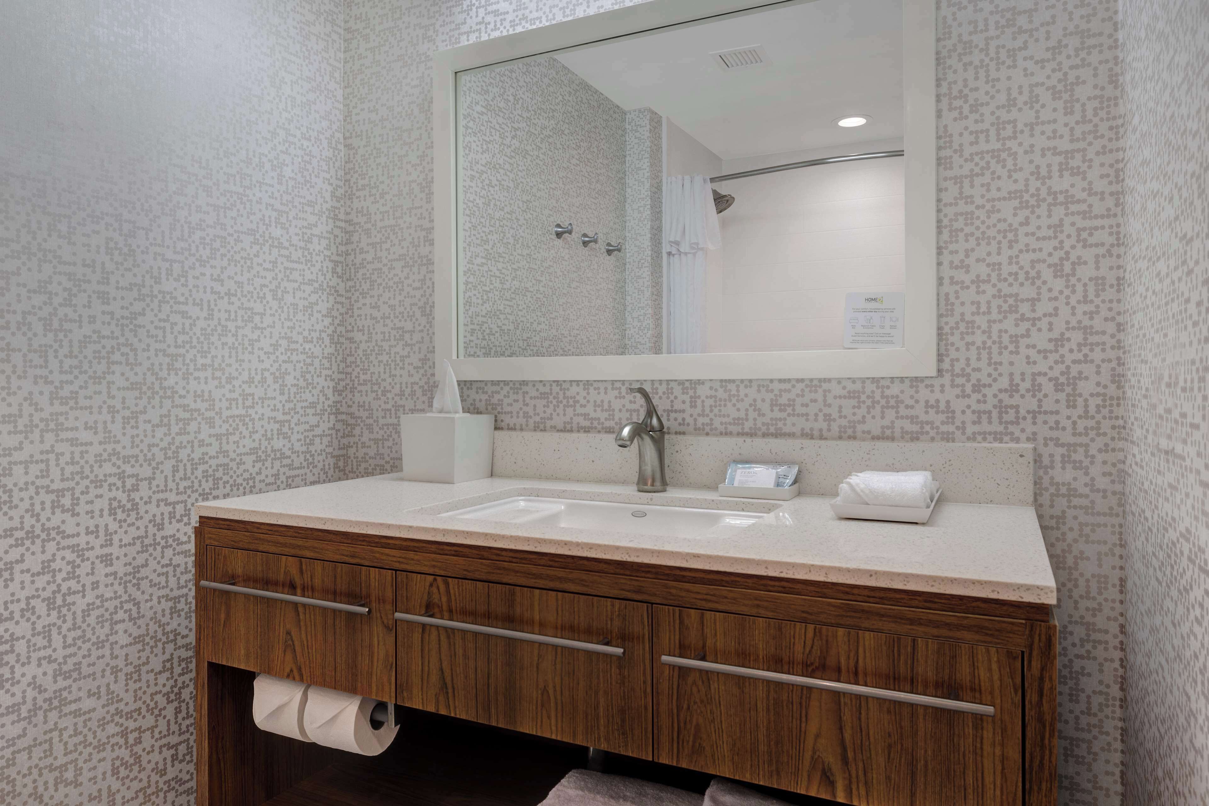 A bathroom with a wooden vanity, a large mirror, and a shower area.
