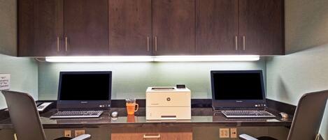 A workspace with two laptops, two HP printers, and two chairs.