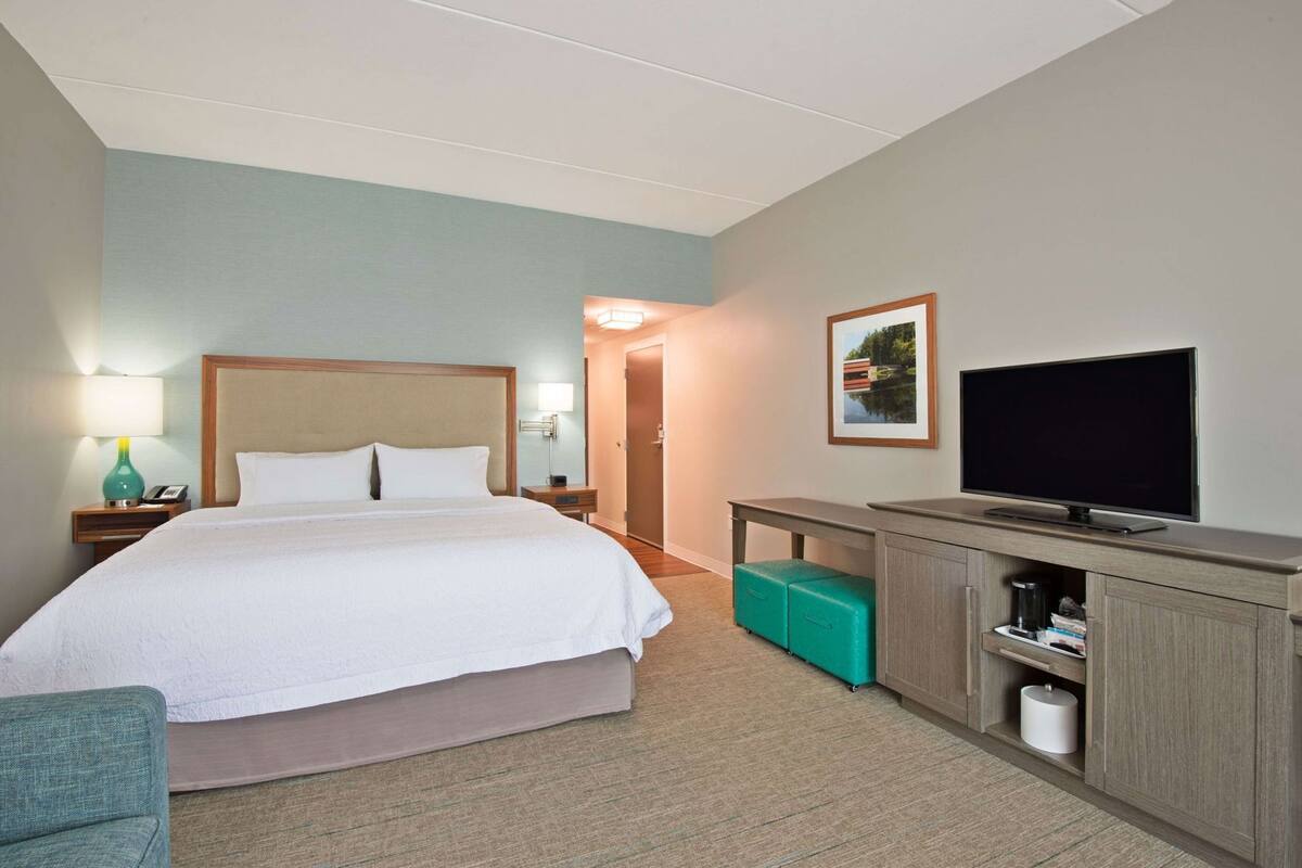 Ein Hotelzimmer mit Bett, Fernseher, Schreibtisch und Stuhl.