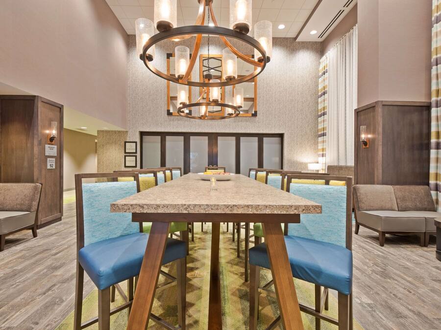 Un salón de conferencias con una gran mesa, sillas cómodas con acolchado azul, piso de madera y un candelabro.