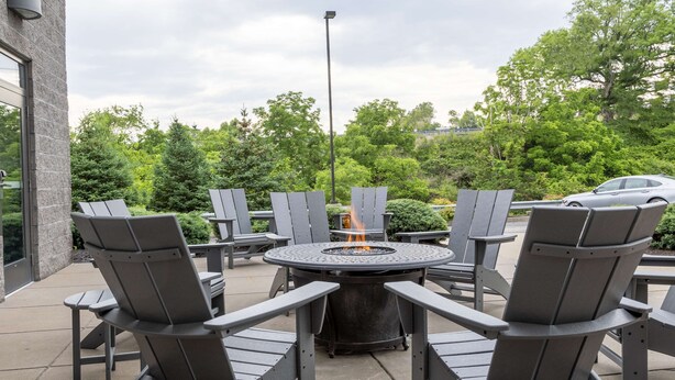 Un espace extérieur aménagé avec des chaises Adirondack et un foyer central.