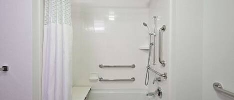 A white bathroom with a bathtub, shower, and grab bars.