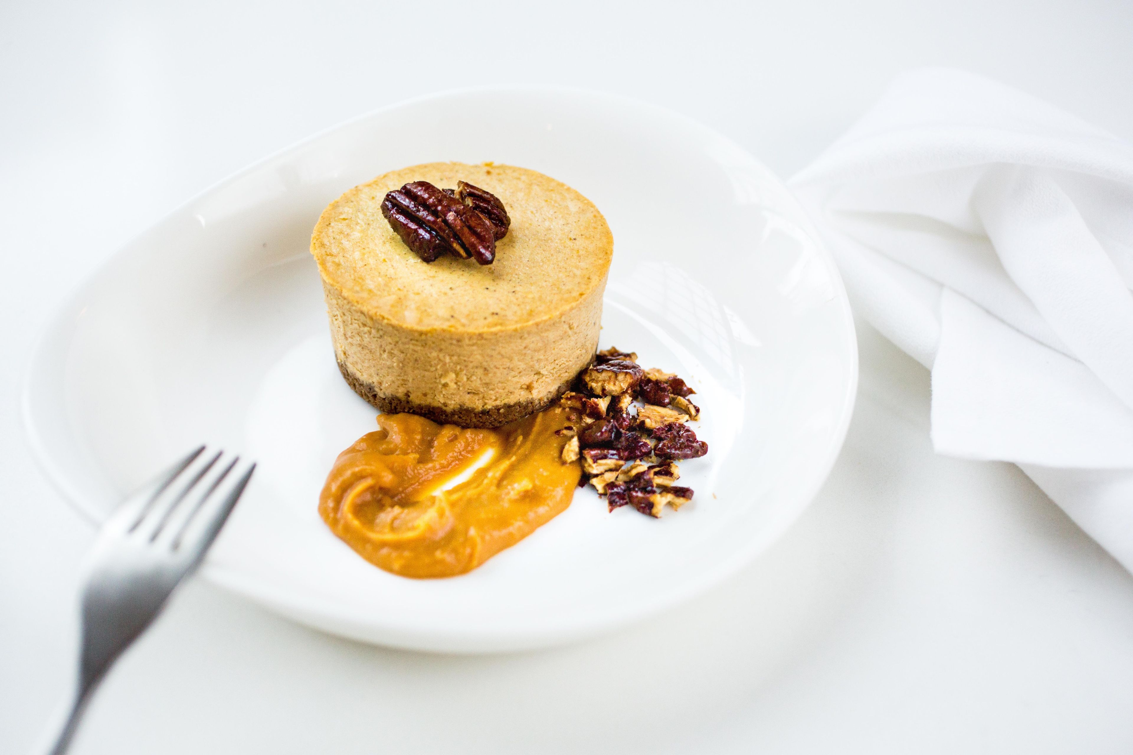 A dessert on a white plate with pecans and a sauce.