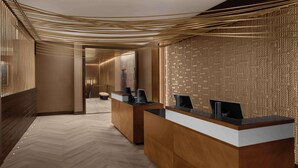 A reception area with a herringbone floor and a reception desk with a computer and a phone. - Hilton Brooklyn New York (Brooklyn)