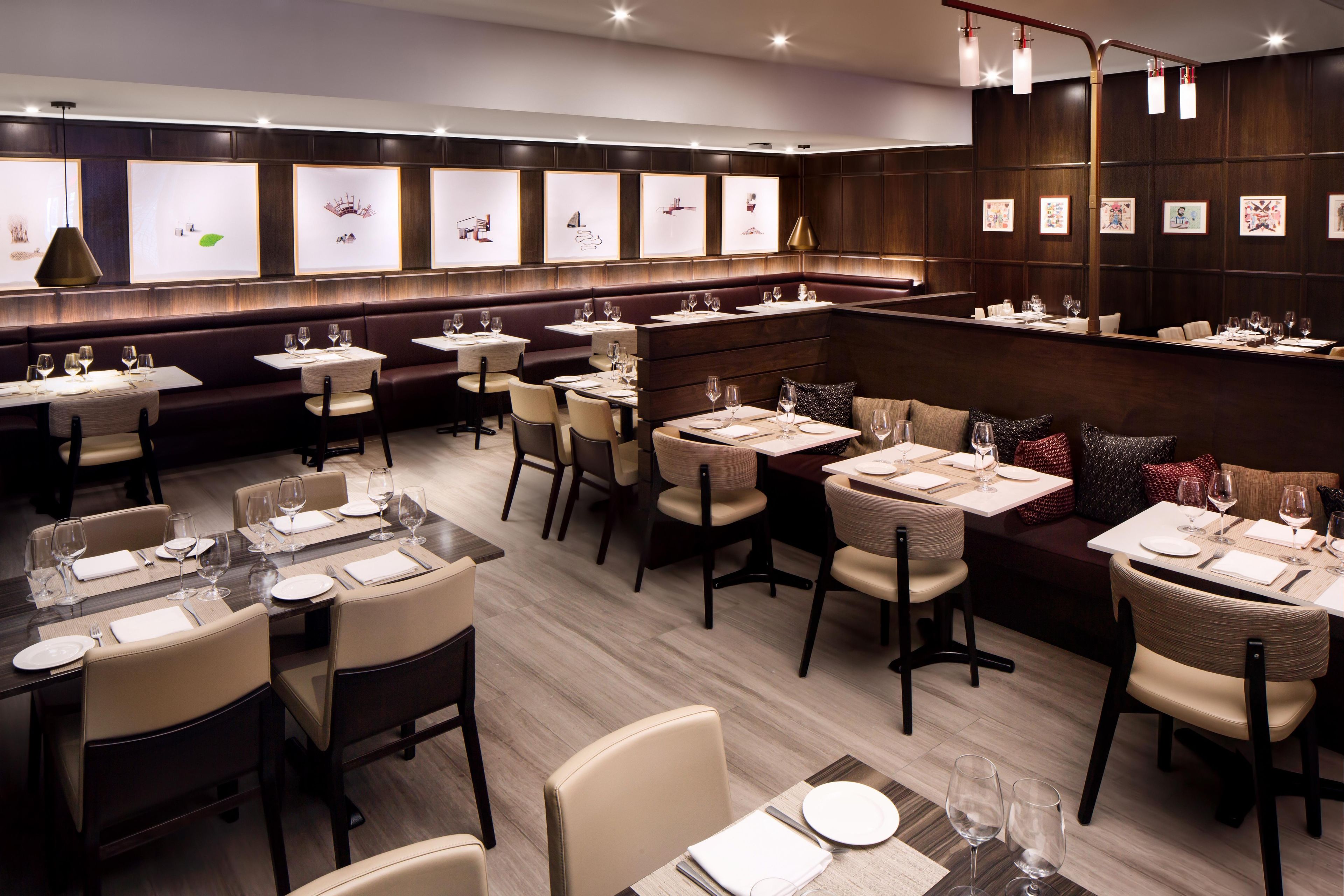 Interior de restaurante con cabinas, mesas y cuadros en las paredes.