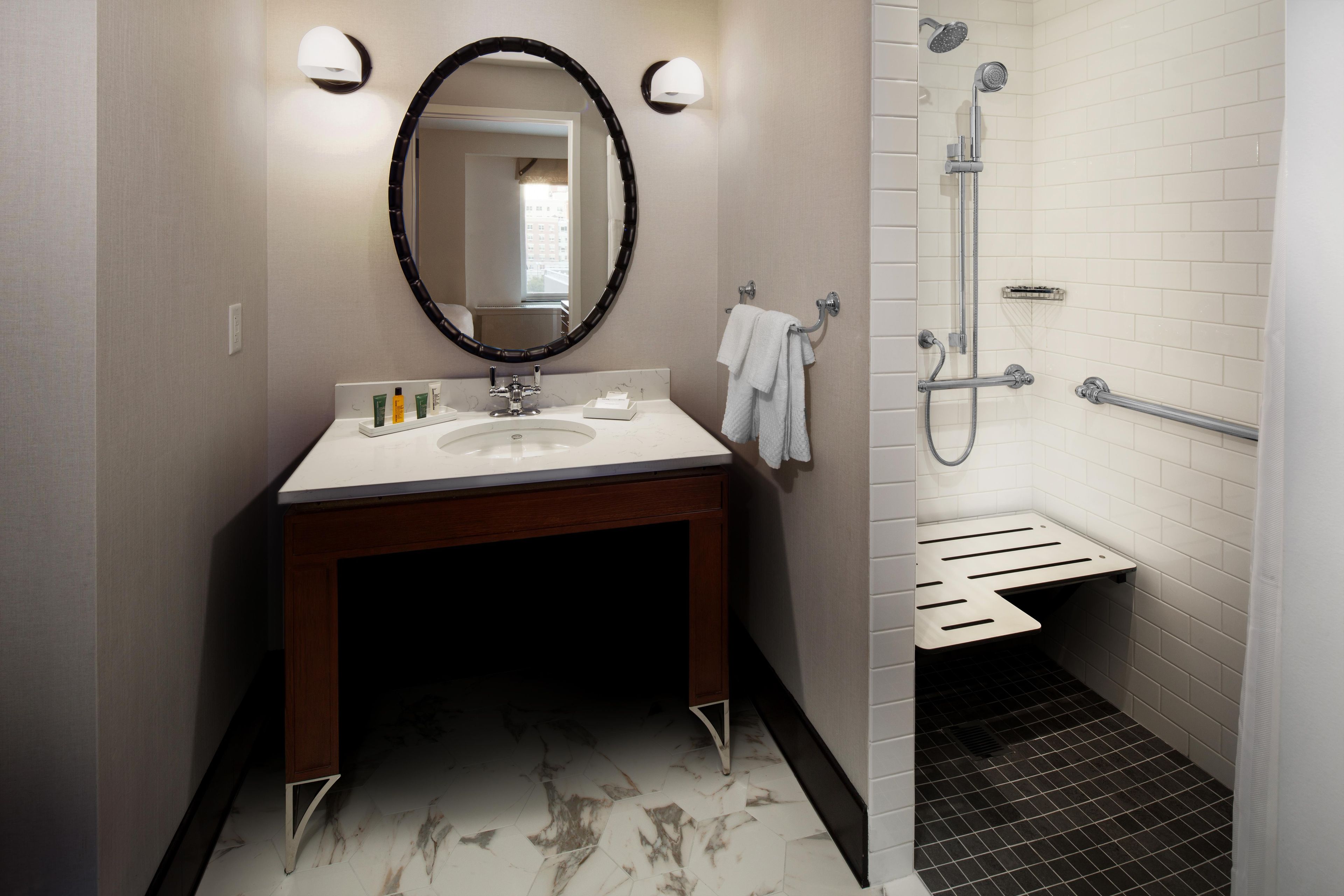 A bathroom with a sink, mirror, towel rack, and shower area.