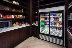 A snack bar with a microwave, shelves stocked with snacks, and a beverage refrigerator.