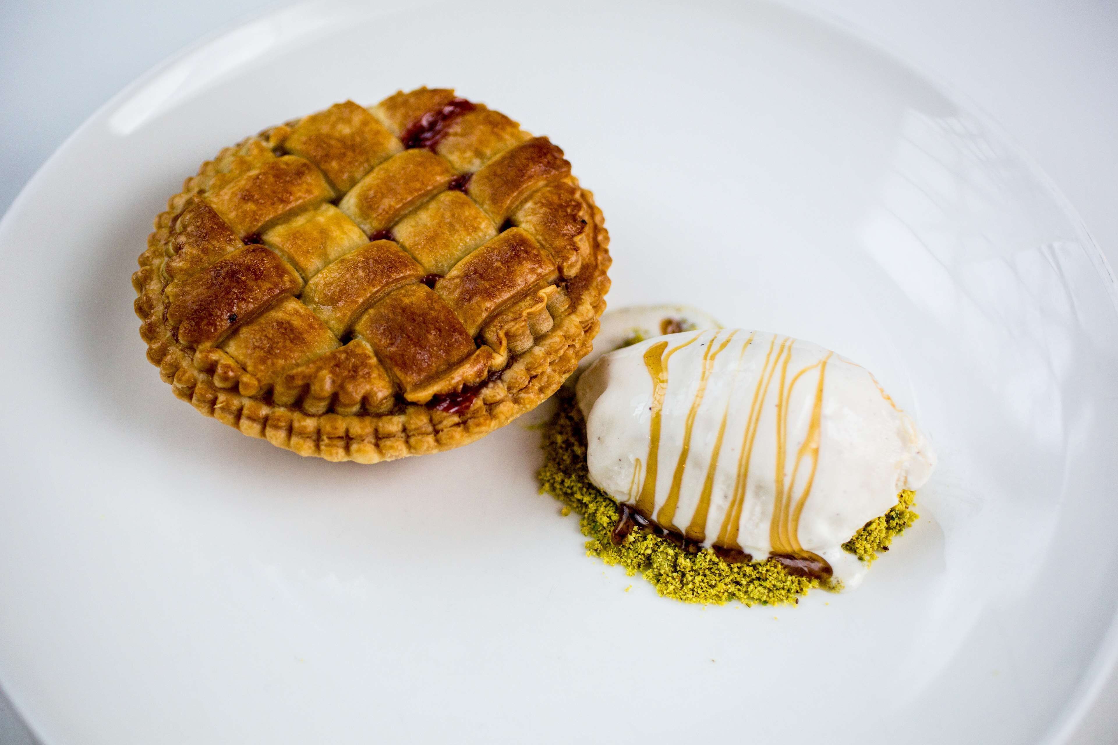 A pie with a lattice crust and a scoop of ice cream with drizzled caramel sauce.