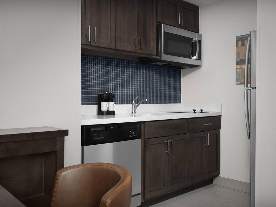 Una cocina moderna con armarios de madera oscura, un microondas de acero inoxidable y un lavavajillas.