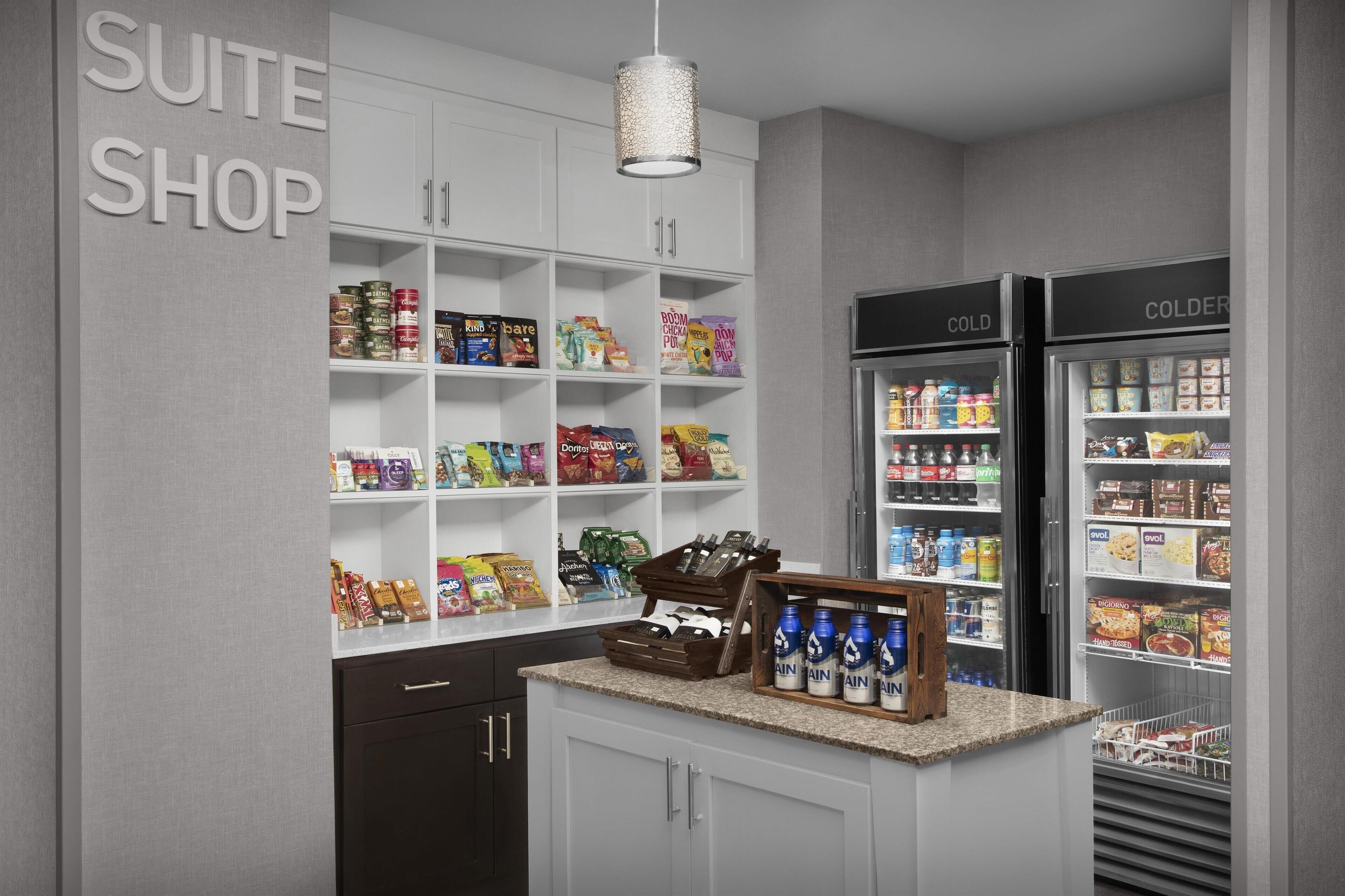 Een kitchenette met witte kastjes, een aanrecht en een inbouwkoelkast.