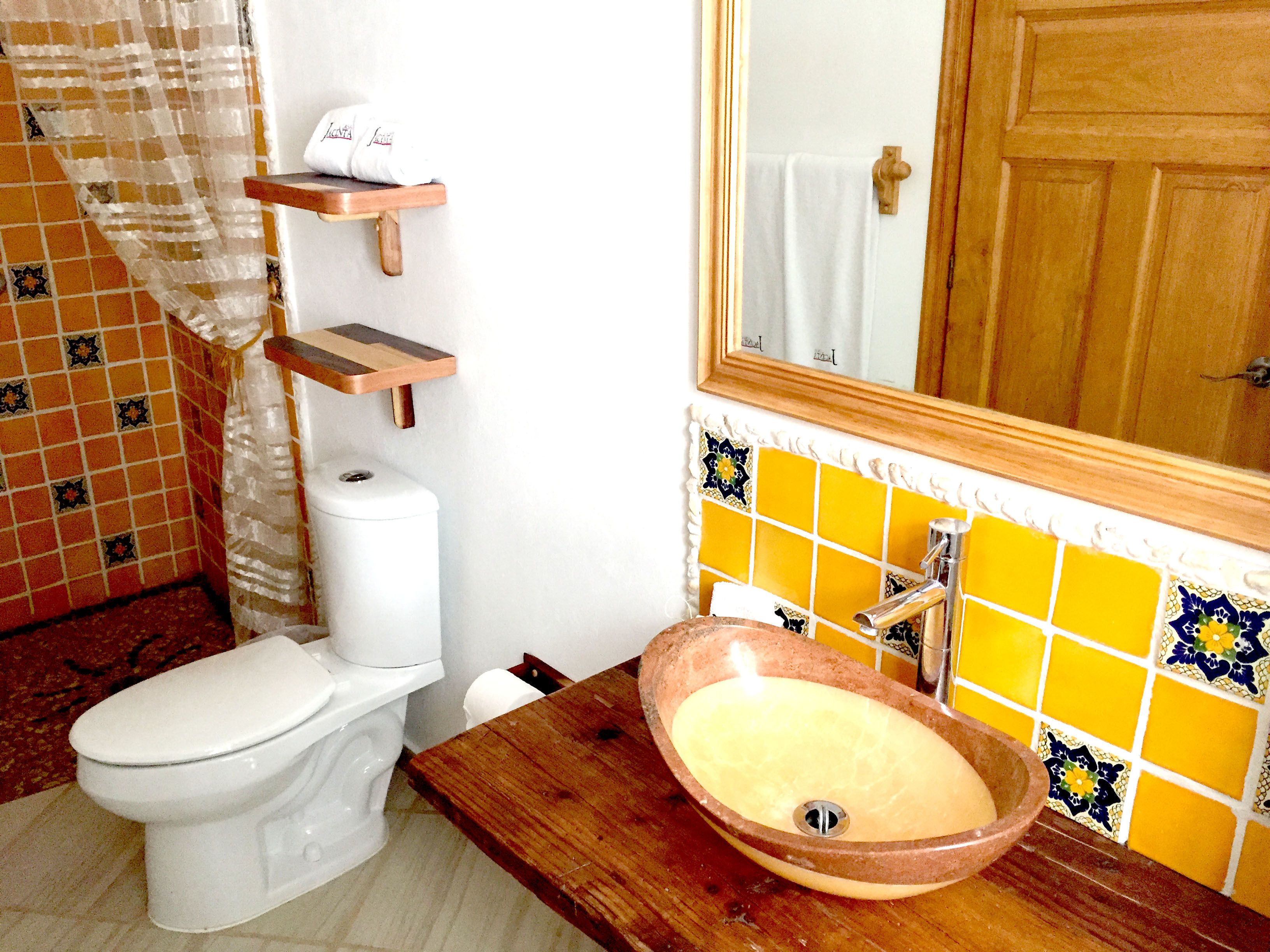 A bathroom with a toilet, a sink with a basin, a towel rack, and a mirror.