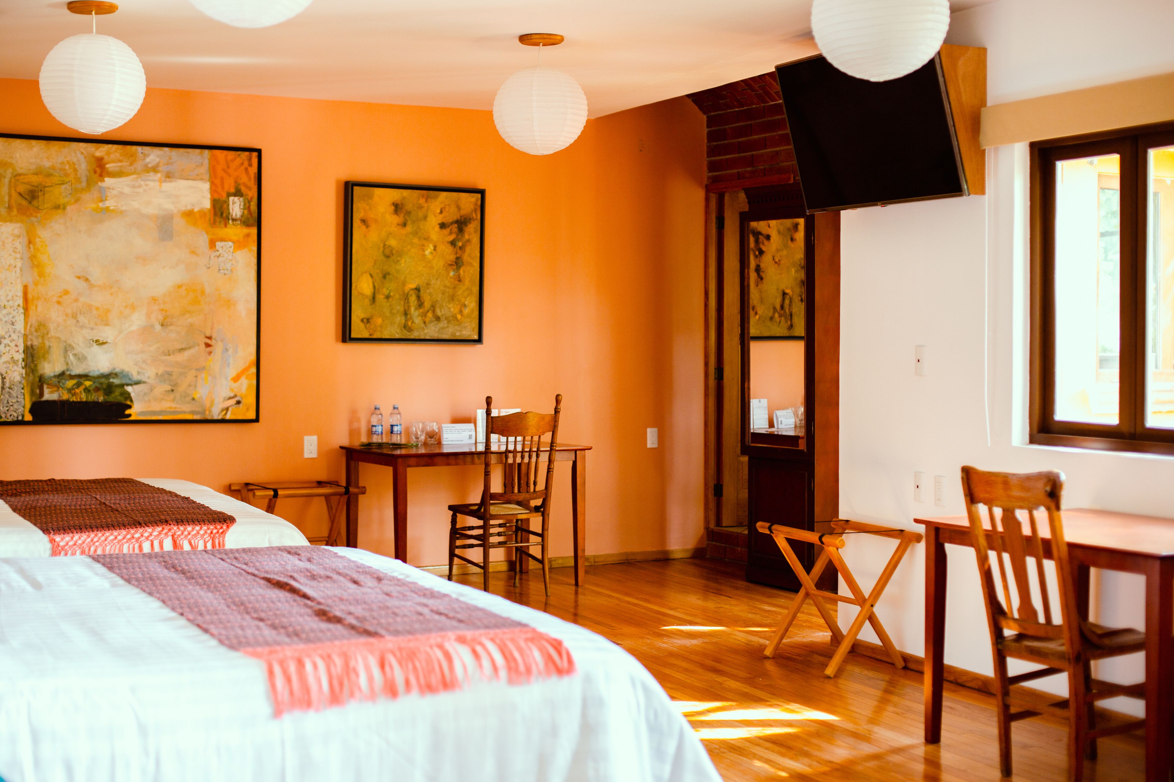 A hotel room with two beds, a desk, and a TV.