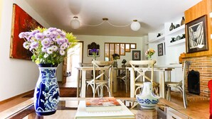 A dining area with a wooden table, chairs, and a vase of flowers. - Casa Jacinta Guest House (Mexico City)