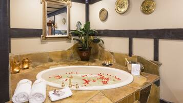 A bathroom with a stone bathtub, a large mirror, and decorative plates on the wall.