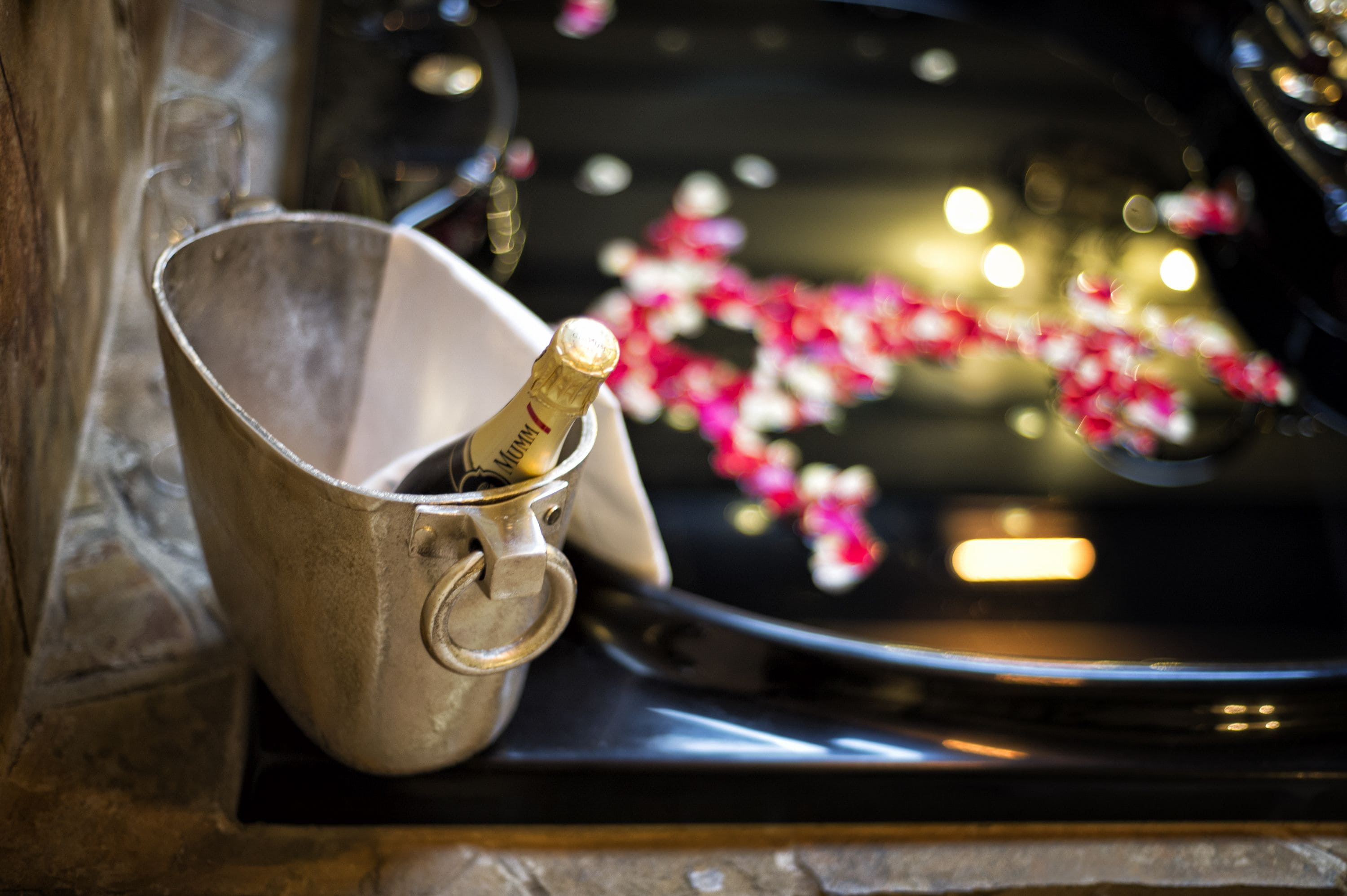 A champagne bottle in a metal bucket on a car's hood.