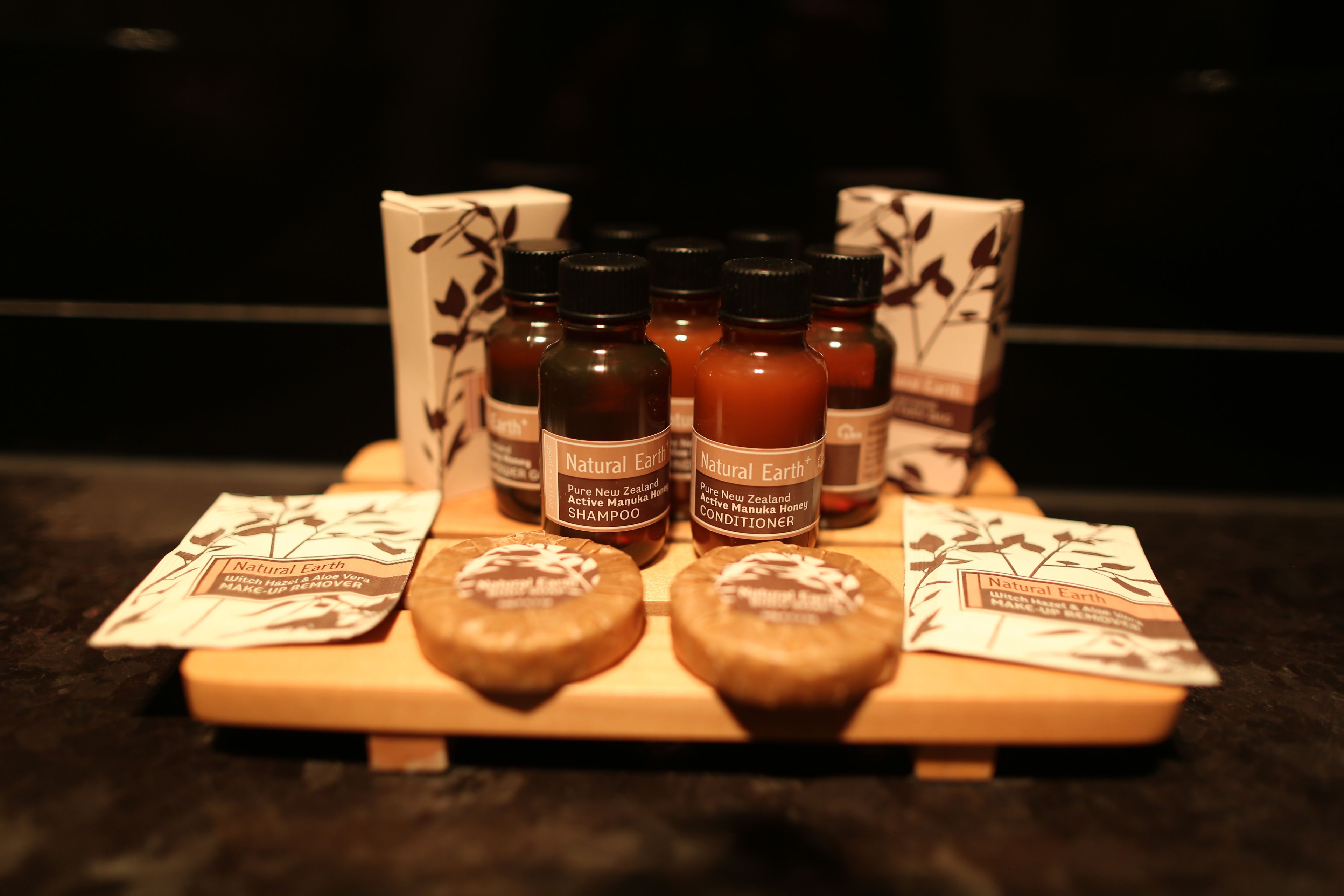 A display of Natural Earth products including shampoo, conditioner, and a face mask on a wooden tray.
