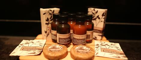A display of Natural Earth products including shampoo, conditioner, and a face mask on a wooden tray.
