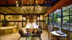 A bedroom with a four-poster bed, a chandelier, a large window, and a view of greenery. - Aquila Nova Retreat (The Patch)