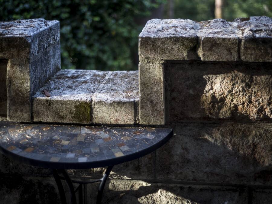 Un banco de piedra con una mesa de mosaico frente a un muro de piedra.
