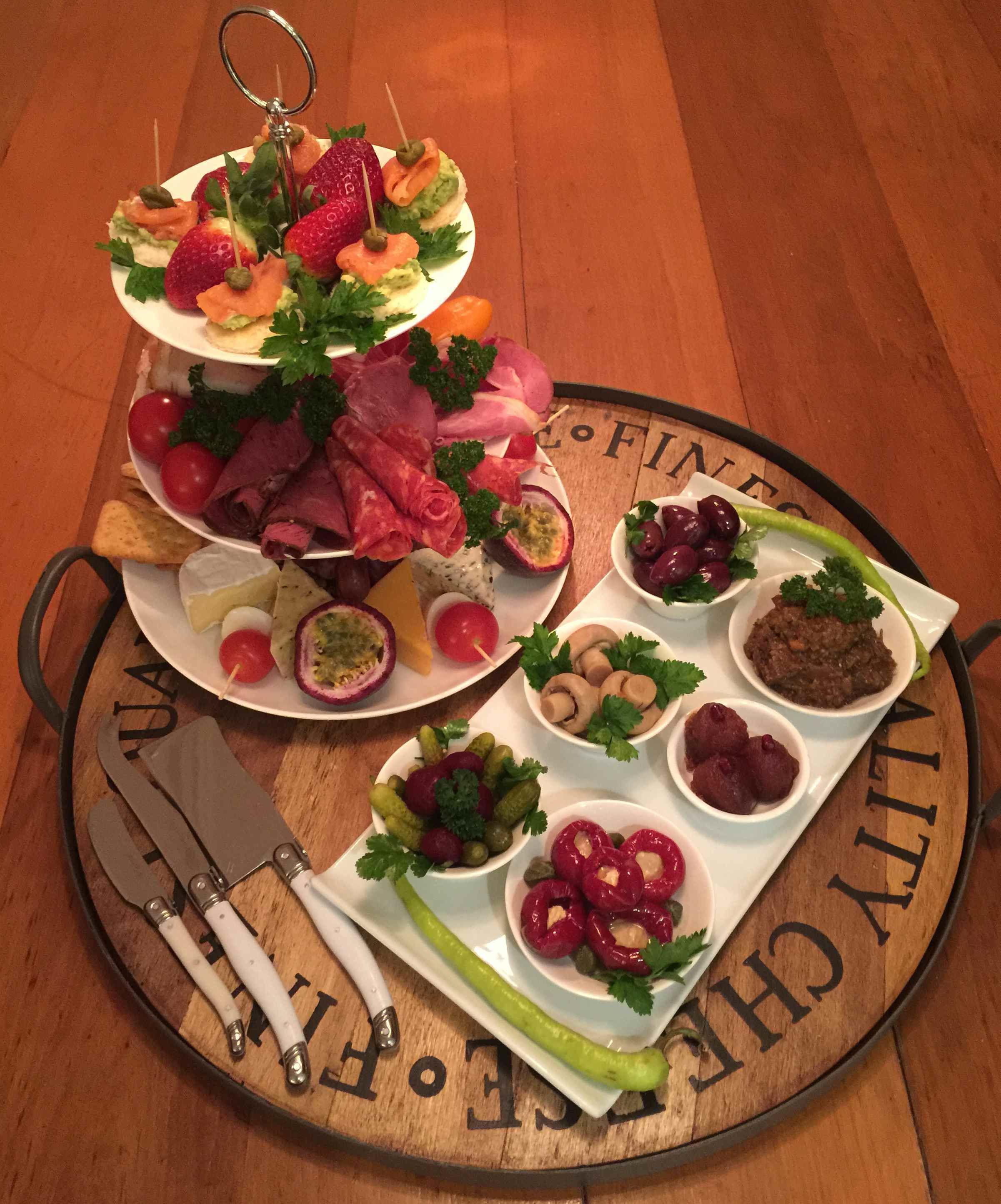A wooden serving tray with a variety of food items including fruits, cheeses, and meats, arranged on a table with a wooden surface.