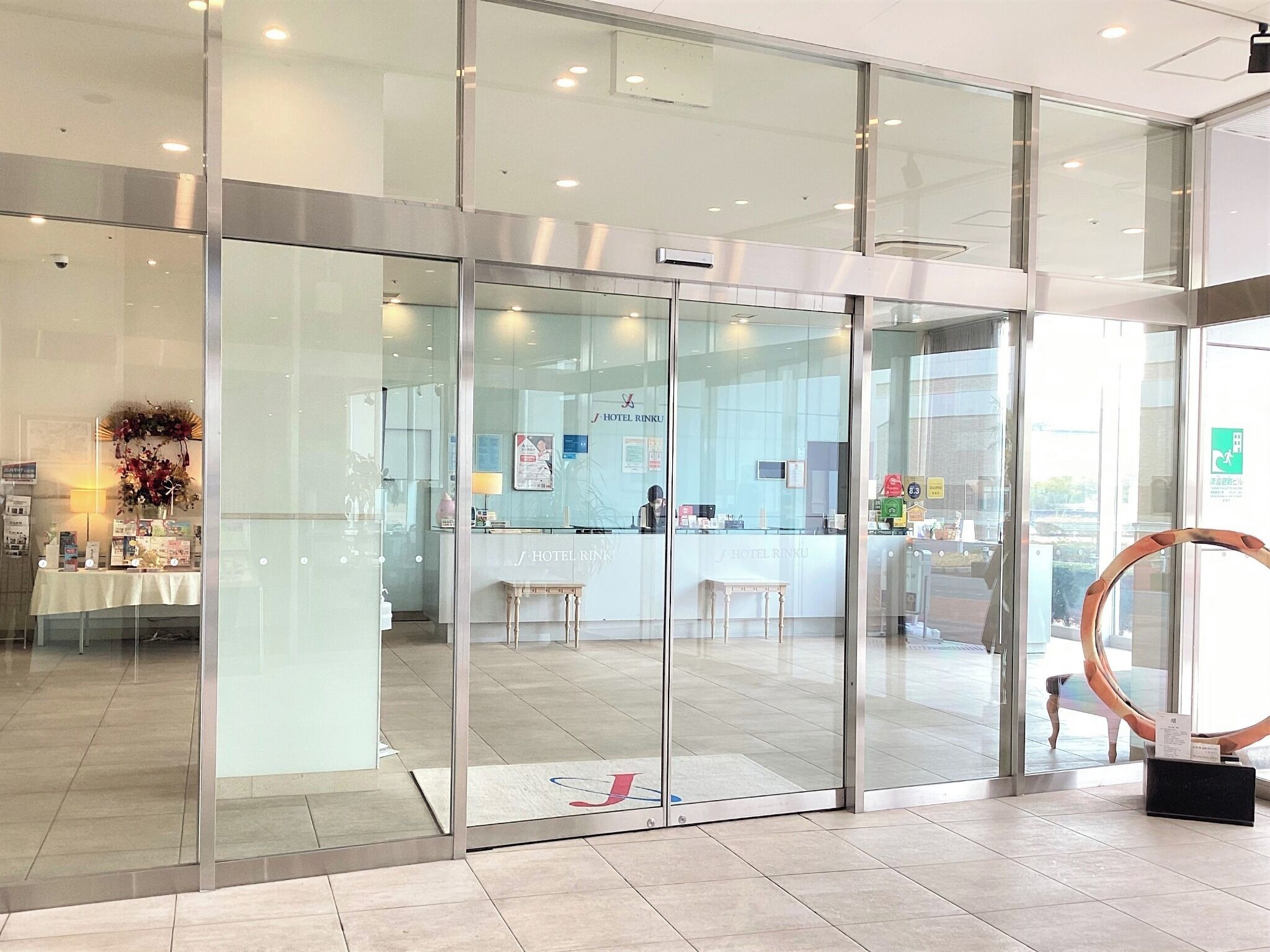A hotel reception area with glass doors, a reception desk, and a visible sign for Hotel Rinku.