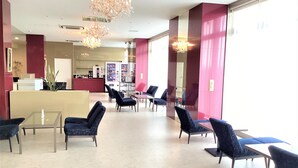 A hotel lobby with a reception desk, seating area, and vending machines. - J Hotel Rinku (Tokoname)