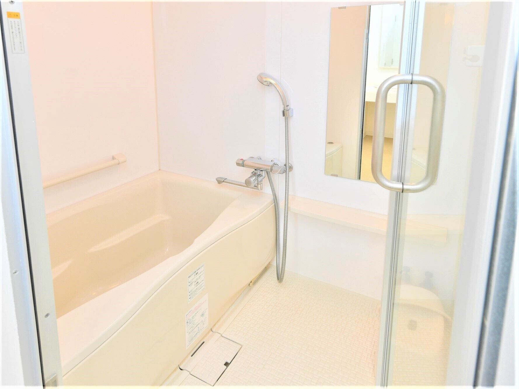 Een badkamer met een bad, een douche en een spiegel.