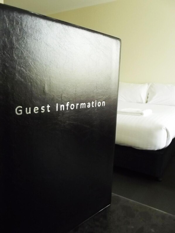 A black box labeled "Guest Information" in a hotel room with a bed and a plain wall in the background. - Heyfield Railway Hotel (Heyfield)