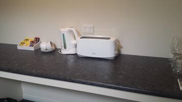 A kitchen counter with a toaster, a kettle, and a box of condiments.