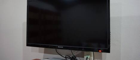 Un televisor de pantalla plana montado en la pared con un estante de madera debajo.