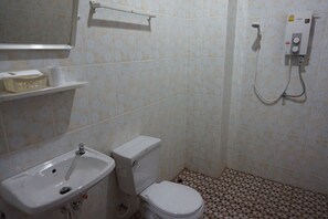 Un baño pequeño con inodoro, lavamanos y ducha. Hay repisas con artículos de aseo personal y un perchero para toallas.
