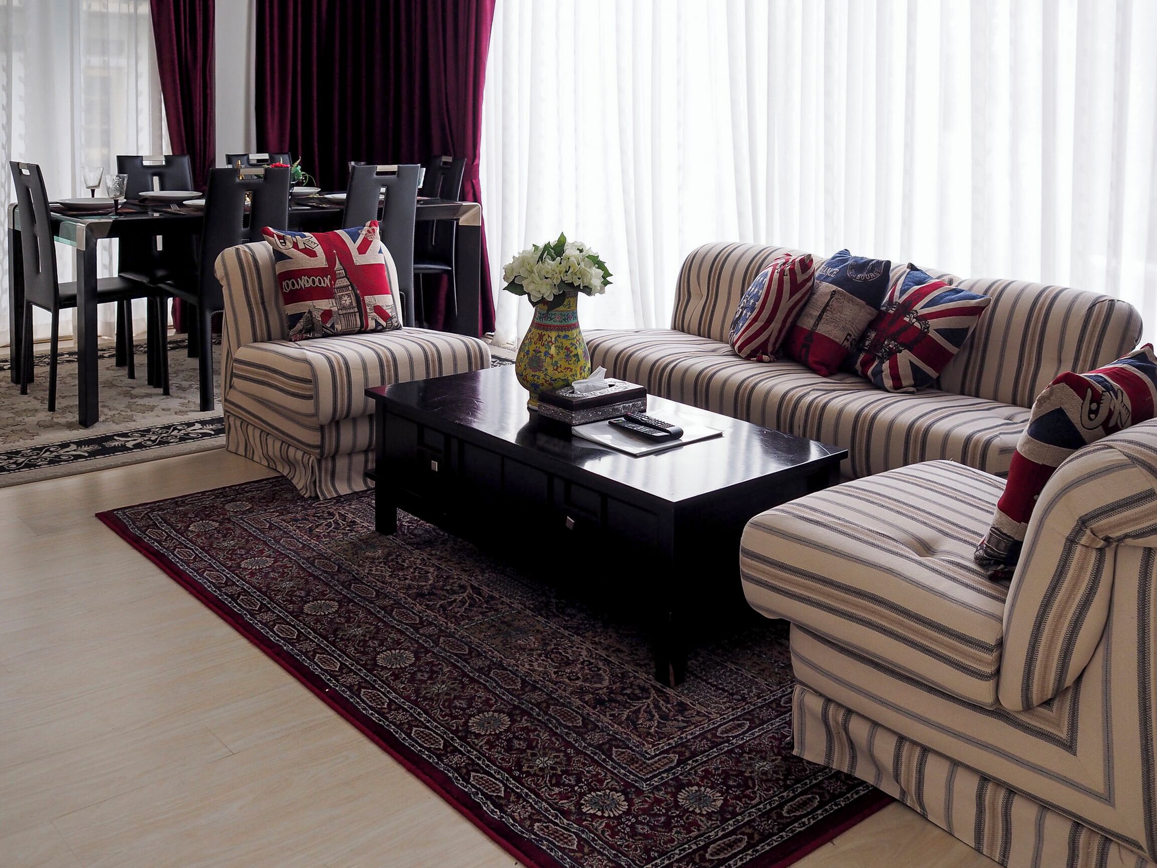 A living room with striped sofas, a coffee table, and a dining area with a table and chairs.