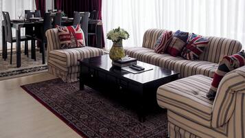A living room with striped sofas, a coffee table, and a dining area with a table and chairs.