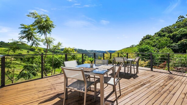 A wooden deck with outdoor furniture, overlooking a lush green landscape and hills. - Top of The Hill (Bald Knob)