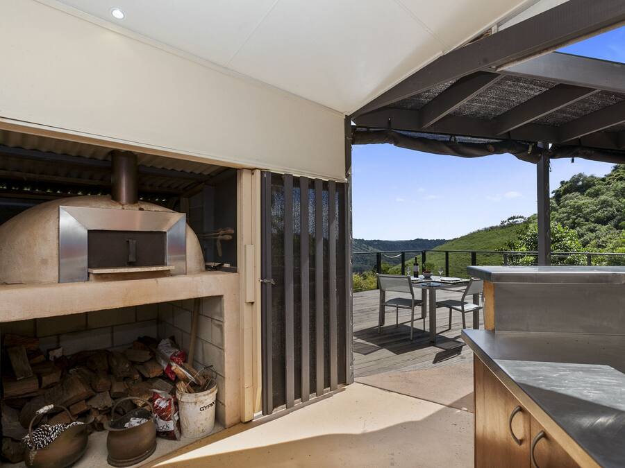 An outdoor kitchen area with a pizza oven, a grill, and a seating area with a table and chairs.