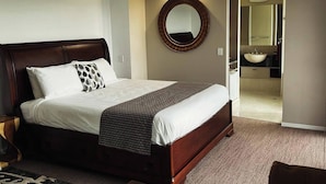 A neatly made bed with a headboard, a round mirror on the wall, and a view into the bathroom. - Top of The Hill (Bald Knob)