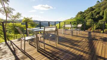 Una terraza de madera con mobiliario exterior y vistas panorámicas.