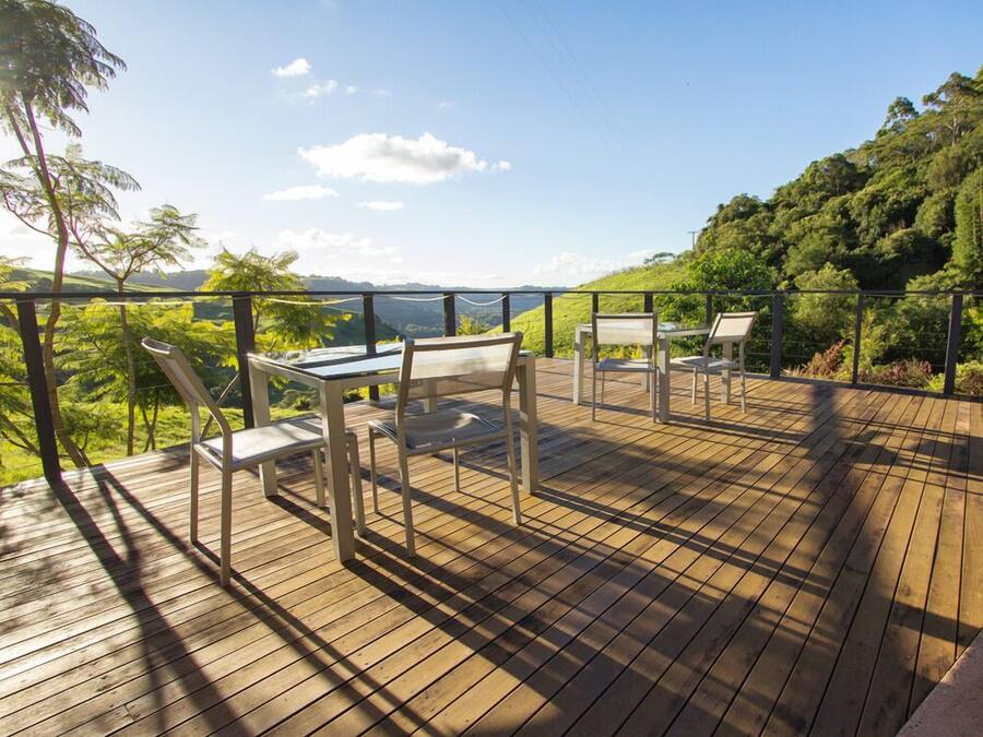 Una terraza de madera con mobiliario exterior y vistas panorámicas.