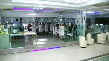 Een modern restaurant met glazen scheidingswanden, witte meubels en paarse verlichtingsaccenten.