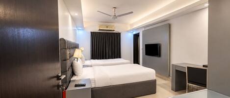 A modern hotel room with a bed, bedside tables, a TV, and a ceiling fan.