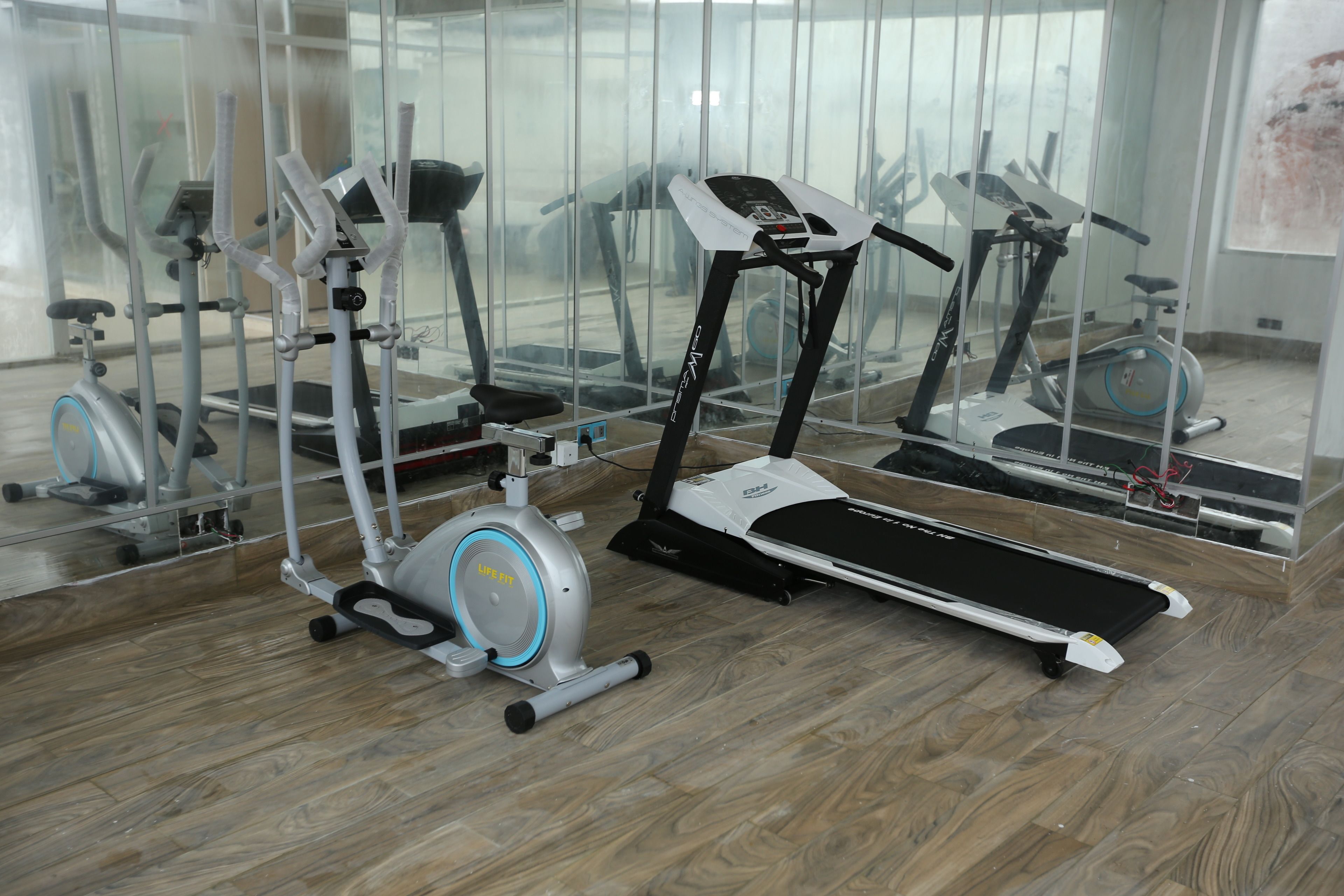 A gym with various exercise equipment, including a treadmill, elliptical, and stationary bikes.