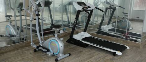 A gym with various exercise equipment, including a treadmill, elliptical, and stationary bikes.