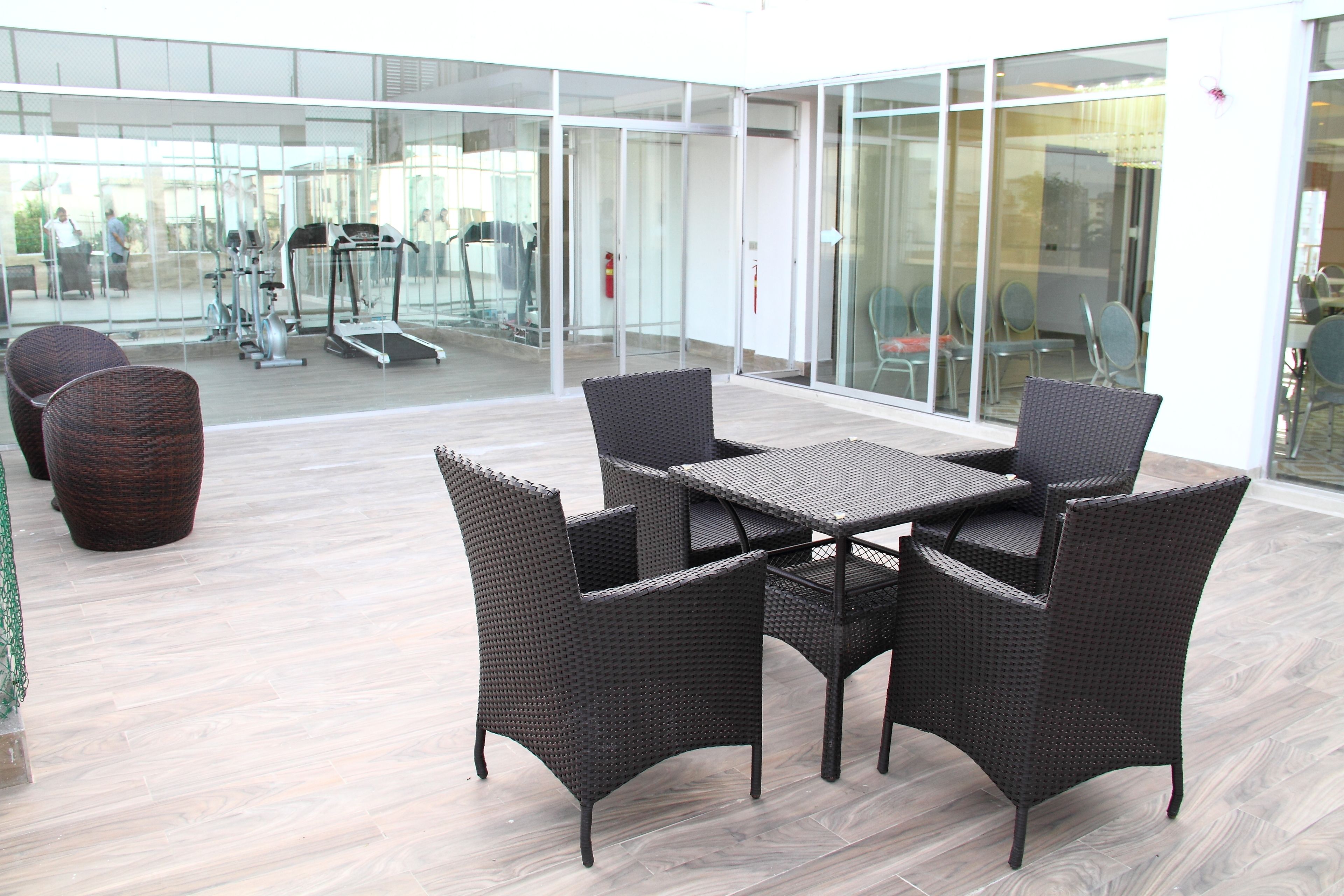 An outdoor seating area with wicker furniture and a view of a gym.