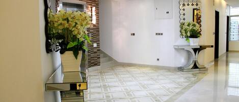 Un intérieur moderne avec un escalier aux surfaces réfléchissantes, un lustre et un revêtement de sol à motifs.
