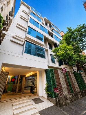 Un edificio moderno con varios pisos, amplias ventanas y una escalera que conduce a la entrada.